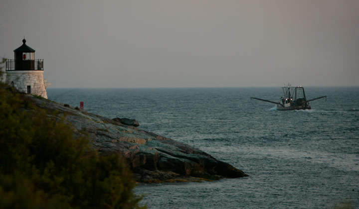 lighthouse in the foreground with a fishing boat in the background